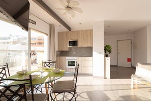 Een modern appartement met een eethoek, kitchenette en een balkon met uitzicht over de stad.