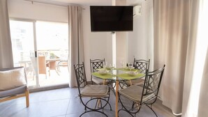 Een eetgedeelte met een ronde tafel, vier stoelen en een flatscreen televisie aan de wand.