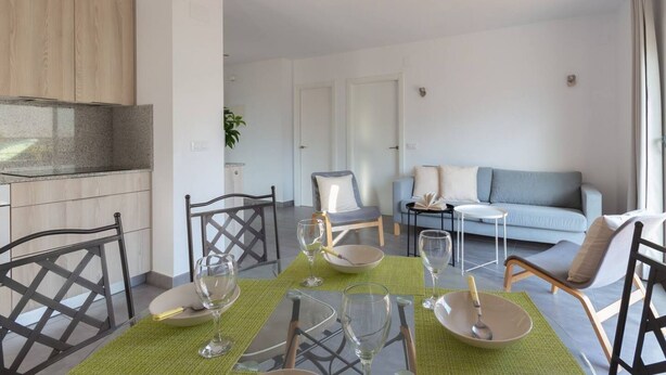 Een moderne woonkamer met een eethoek. Er is een bank, een salontafel en een eettafel met stoelen.