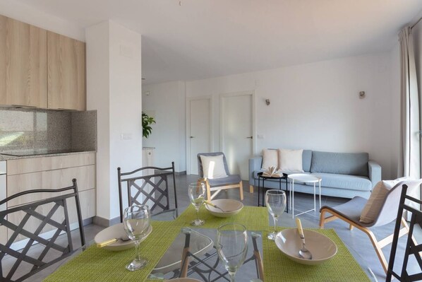 Ein modernes Wohnzimmer mit Essbereich. Es gibt ein Sofa, einen Couchtisch und einen Esstisch mit Stühlen.