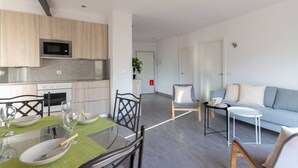 Een moderne woonkamer met een bank, een salontafel en een eethoek met een tafel gedekt voor twee personen.