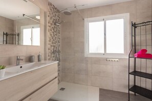 Een moderne badkamer met een douche, wastafel en een raam.