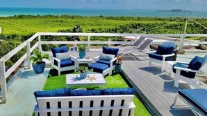 Een terras met witte meubels, een klein tafeltje en planten in potten.