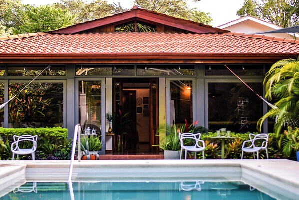 Ein Haus mit Schwimmbad, Sitzgelegenheiten im Freien und einer überdachten Terrasse.
