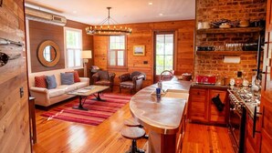 A cozy cabin interior with a wooden interior, a dining area, and a kitchen with a brick wall. - 3BR Family Retreat | EV Charging, Porch & Parking | Walk to MUSC | Charleston (Charleston)