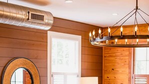A cozy living room with a beige sofa, a wooden coffee table, a leather armchair, and a red striped rug. - 3BR Family Retreat | EV Charging, Porch & Parking | Walk to MUSC | Charleston (Charleston)