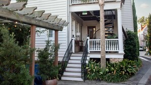 A two-story house with a balcony, a covered porch, and a staircase leading to the entrance. - 3BR Family Retreat | EV Charging, Porch & Parking | Walk to MUSC | Charleston (Charleston)