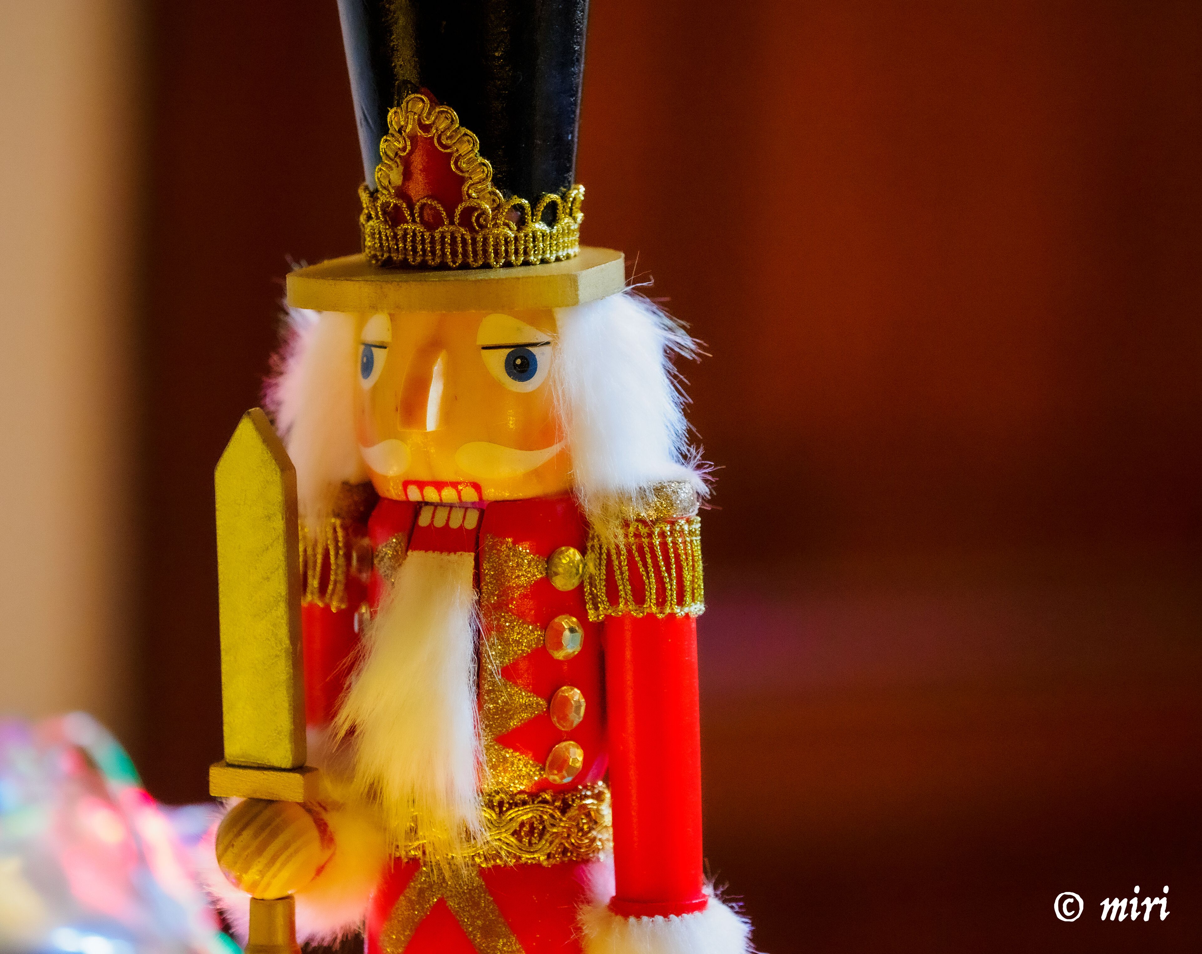 Un cascanueces con traje rojo y dorado, barba blanca y una corona.