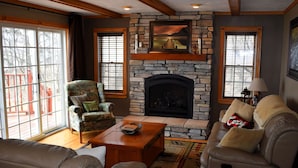 A living room with a stone fireplace, leather sofas, and a wooden coffee table.