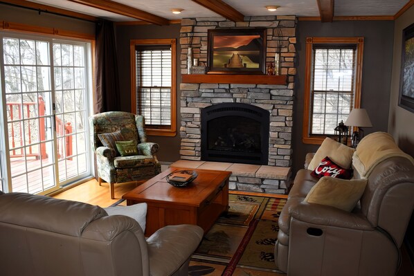 A living room with a stone fireplace, leather sofas, and a wooden coffee table.