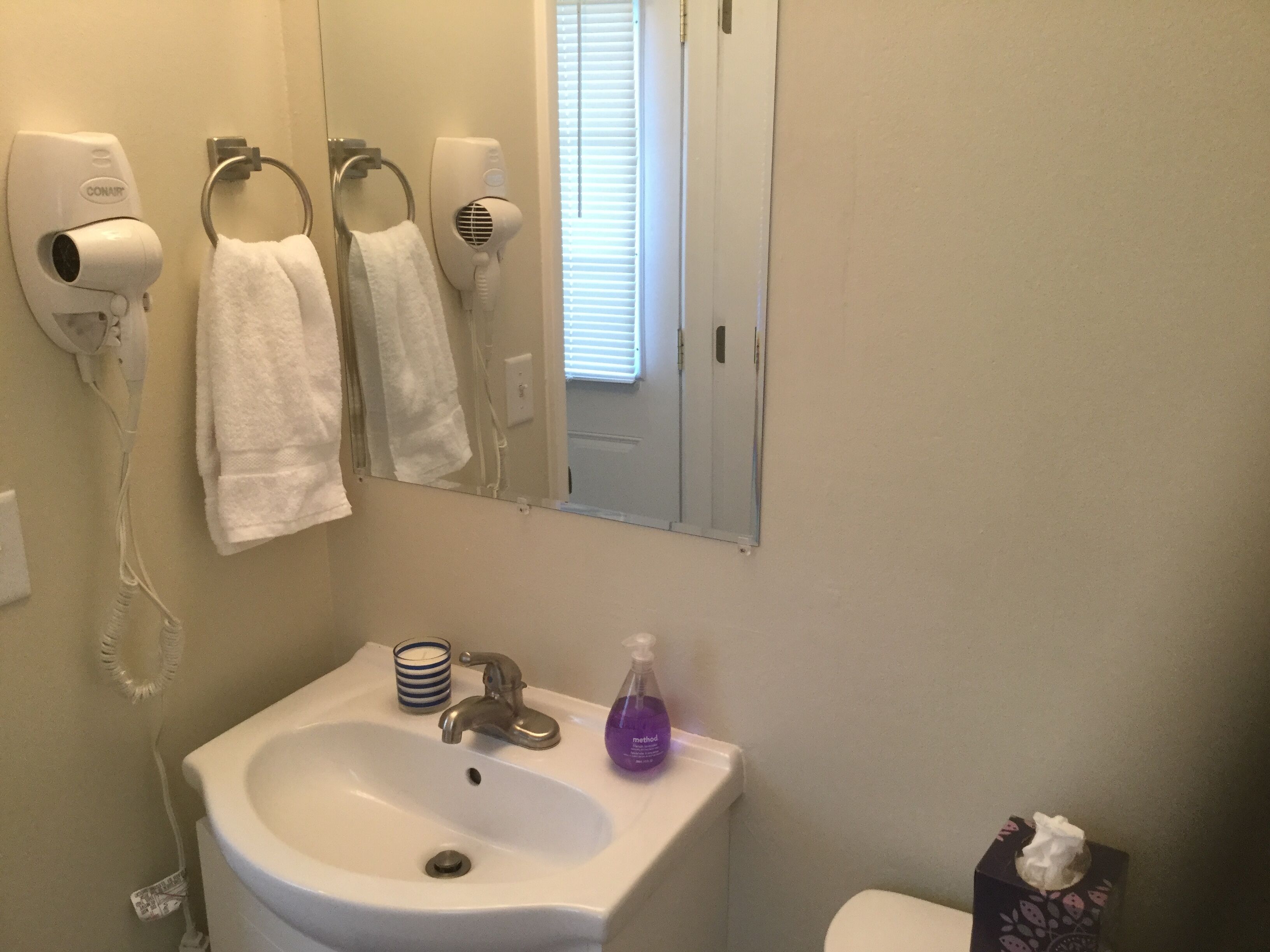 A bathroom with a sink, hand dryers, and a mirror.