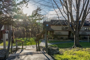 Un barrio residencial con una casa, una escalera de madera y un árbol grande.