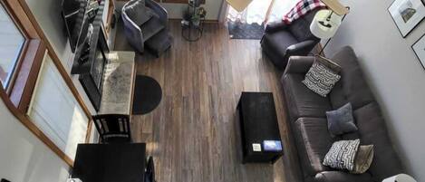 Un salon avec un canapé, une table basse, un téléviseur et un ventilateur de plafond.