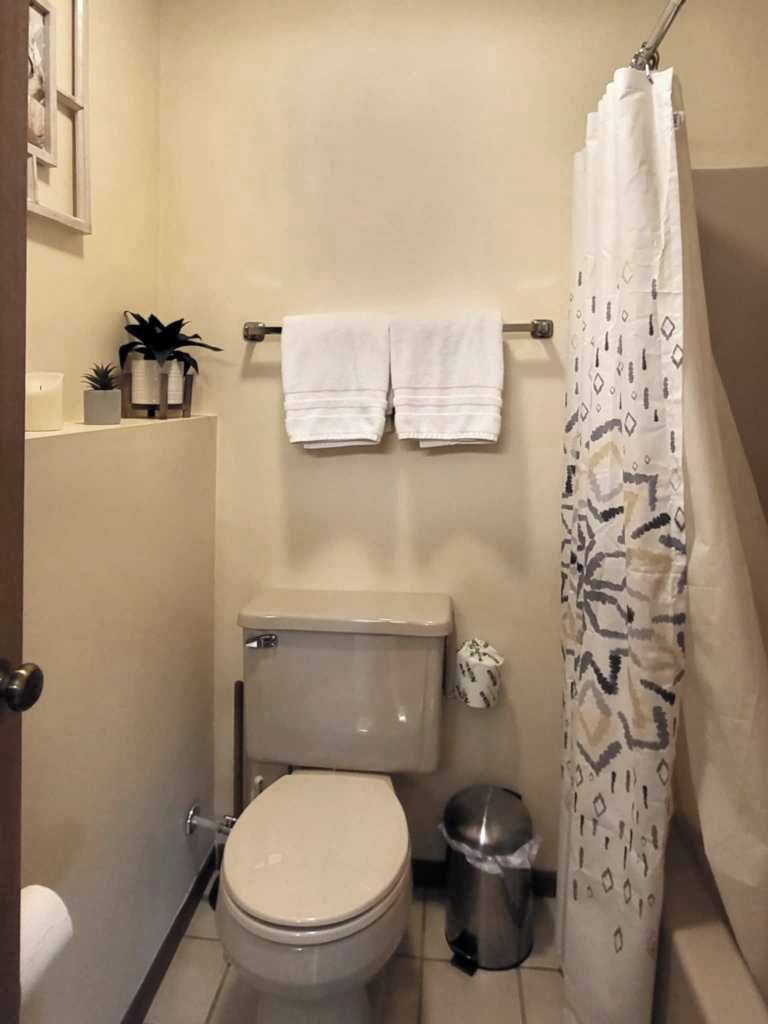 Un baño pequeño con inodoro, cortina de ducha y toallero con dos toallas.
