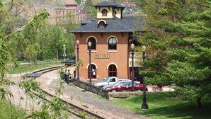Un bâtiment en briques portant l’inscription « GALENA », doté d’un petit balcon, d’une allée couverte et d’un espace de stationnement avec des voitures.