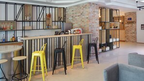 A modern bar area with stools, shelves with bottles, and a brick accent wall. - Aktinia (Nessebar)