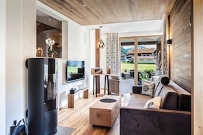 A modern living room with a fireplace, TV, and seating area. - Chalet N ° 4 - Gränobel chalets (Grän)