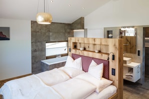 A modern bedroom with a large bed, wooden headboard, bedside tables, and a built-in wardrobe. - Chalet N ° 4 - Gränobel chalets (Grän)