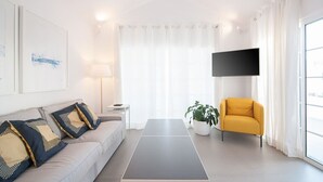 A modern living room with a sofa, a yellow armchair, a flat-screen TV, and a large window with curtains.