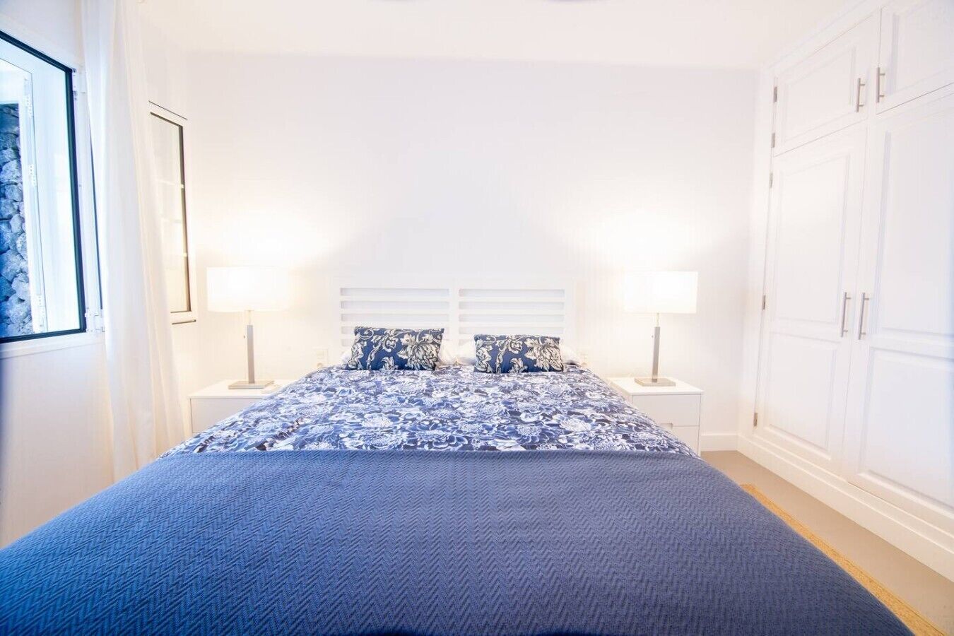 Une chambre à coucher avec un lit, deux tables de chevet et une armoire.
