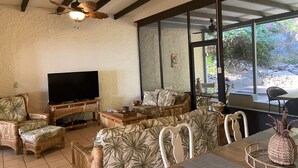 Een woonkamer met een televisie, een bank en een eettafel.