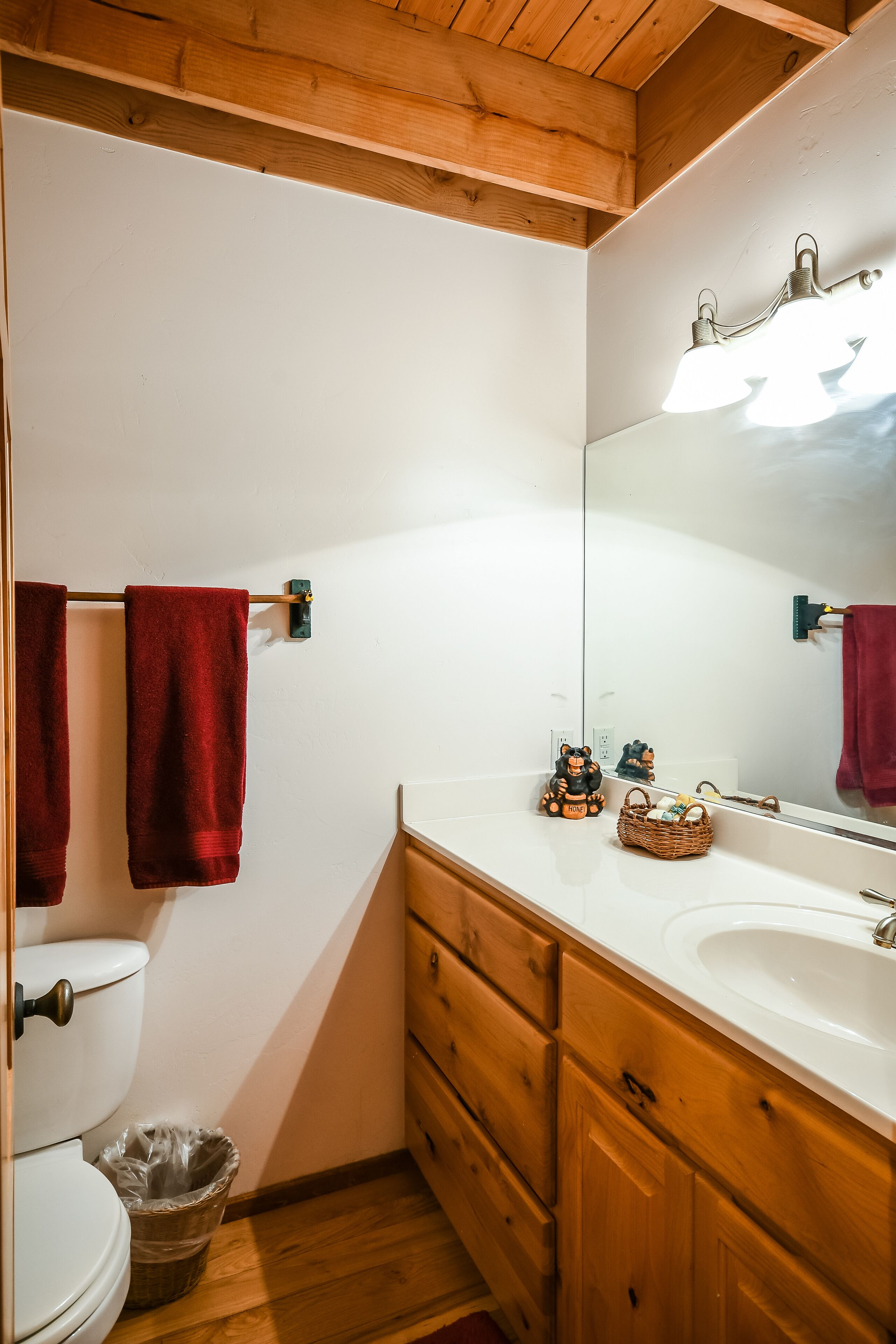 Une salle de bain avec des meubles en bois, un lavabo blanc et un miroir.