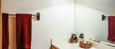 Une salle de bain avec des meubles en bois, un lavabo blanc et un miroir.