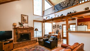 Un salón acogedor con chimenea, sofás de cuero y televisor.