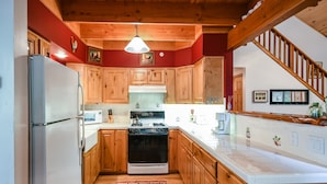 Una cocina con armarios de madera, un refrigerador, una estufa y un microondas.