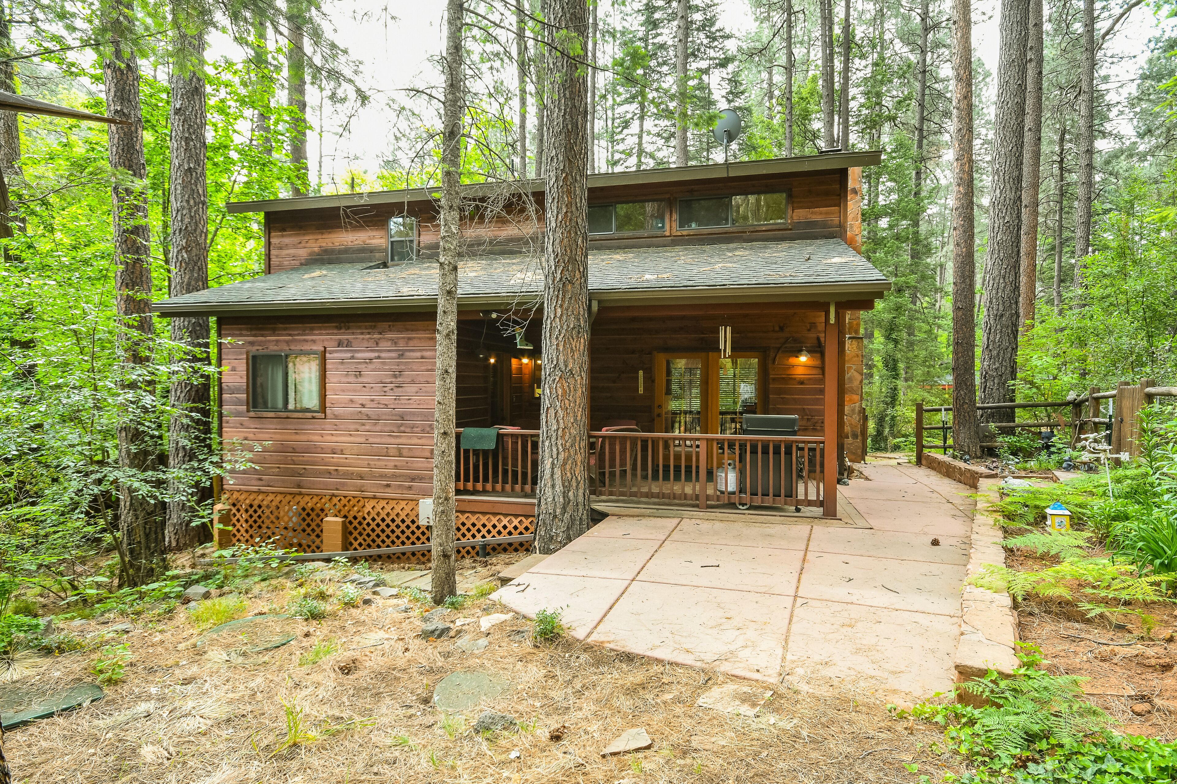 A two-story log cabin with a deck and a covered outdoor seating area.