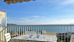 A table set for two with a view of the sea, covered with a beach-themed tablecloth. - Seafront studio with private parking - Le Lavandou (Le Lavandou)