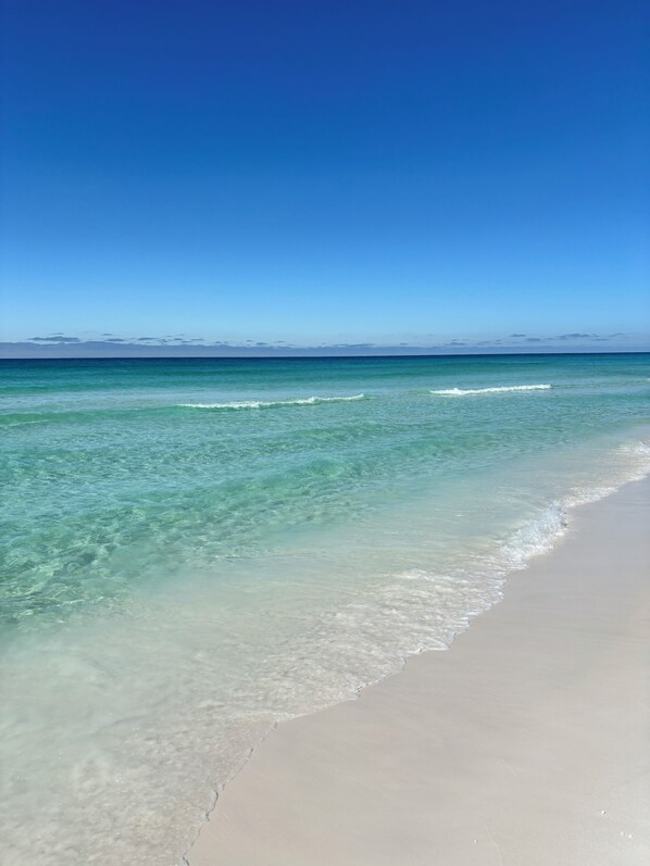 A beach with clear water and a wide sandy shore.