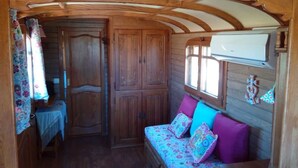 A cozy interior with a wooden bench, a table, and a wardrobe. - Roulotte La Nanouche (Le Cailar)