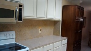 A kitchen with white cabinets, a microwave, a stove, and a wooden cabinet. - Beauvoir (Beautiful View) (Biloxi)