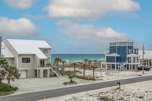 A coastal property with a two-story house and a separate building, both featuring balconies and a view of the ocean.