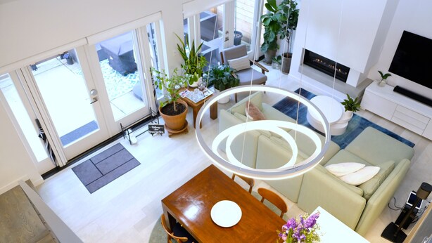 Ein modernes Wohnzimmer mit Essbereich, großen Fenstern und einem Kamin.