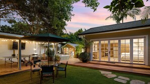 A backyard with a dining area, a covered patio, and a large sliding glass door leading to a bedroom.