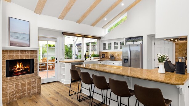 A modern kitchen with a built-in fireplace, bar stools, and a large island.