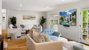 A modern living room with a sofa set, a blue armchair, and a large painting of a waterfall.