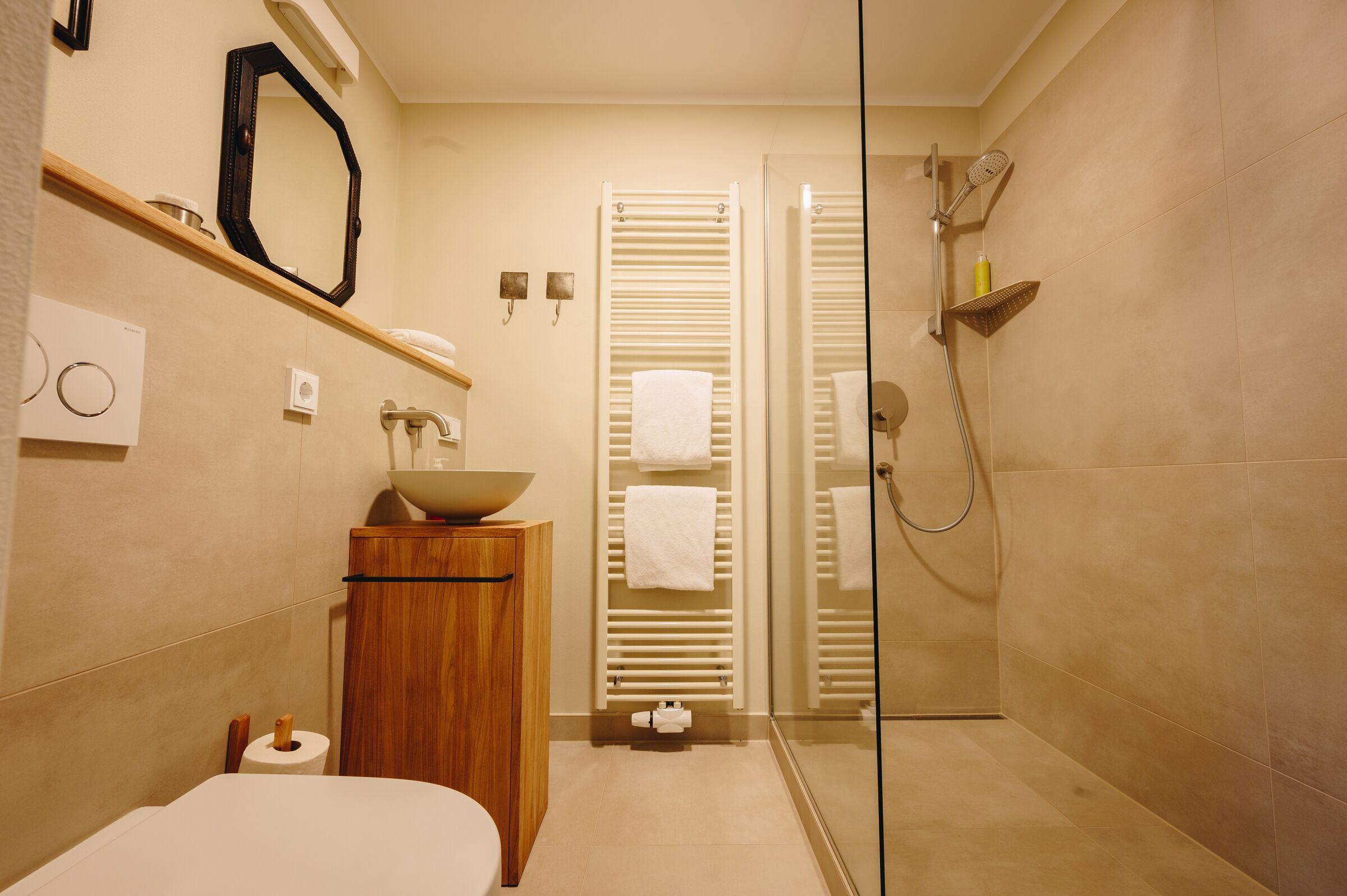 Ein modernes Badezimmer mit Duschkabine aus Glas, einem Holzbadezimmer-Möbel, einem Waschbecken und einer Toilette.