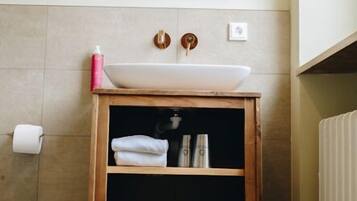 Ein Badezimmer mit einem Holzkosmetikschrank, einem weißen Waschbecken, einem Spiegel und einem Handtuchhalter.