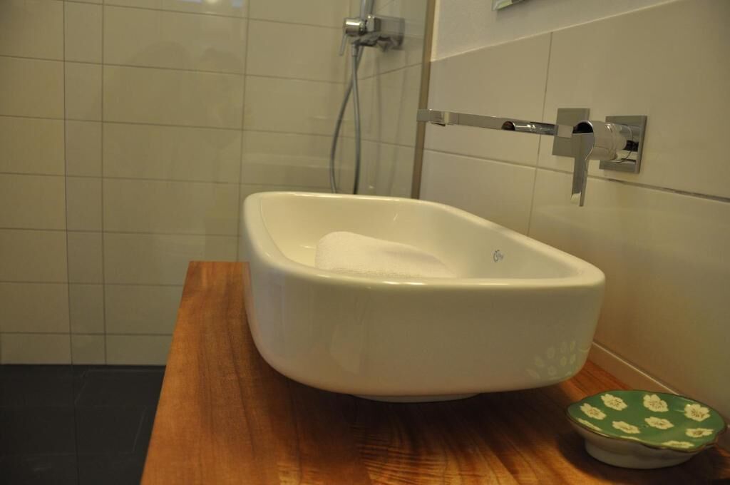 A bathroom with a white bathtub, a wooden countertop, and a green floral-patterned soap dish.