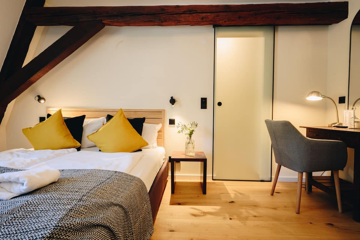 Une chambre à coucher avec un lit, une table de chevet, une lampe, une chaise et une porte.