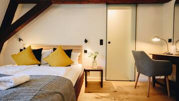 Ein Schlafzimmer mit Bett, Nachttisch, Lampe, Stuhl und einer Tür.