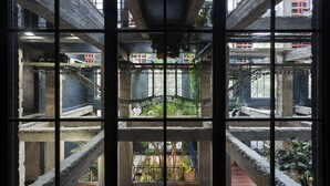 Interior com vários níveis, vigas de concreto aparente e uma escadaria central.
