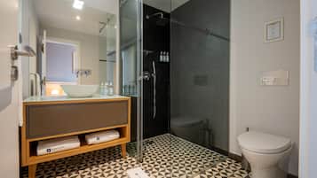 A modern bathroom with a glass-enclosed shower, a white sink, and a toilet.