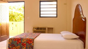 A bedroom with a bed, a window, an air conditioning unit, and a door leading to an outdoor area. - Hotel Le Meridien (Les Cayes)