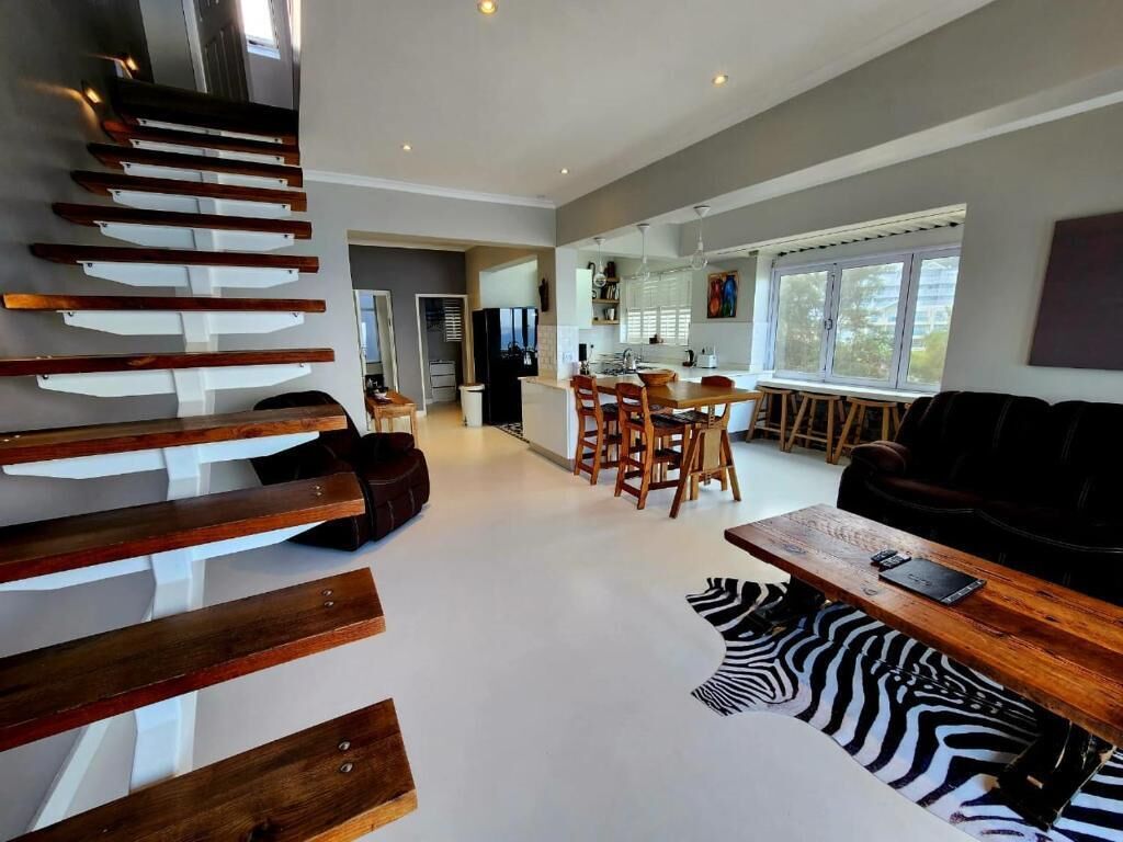 A modern living space with a staircase, a dining area, and a sofa.