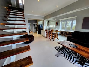 Un espacio habitable moderno con una escalera, un comedor y un sofá.