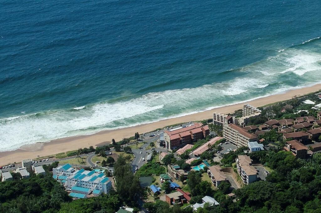 A coastal town with a beachfront hotel, a sandy beach, and residential buildings.